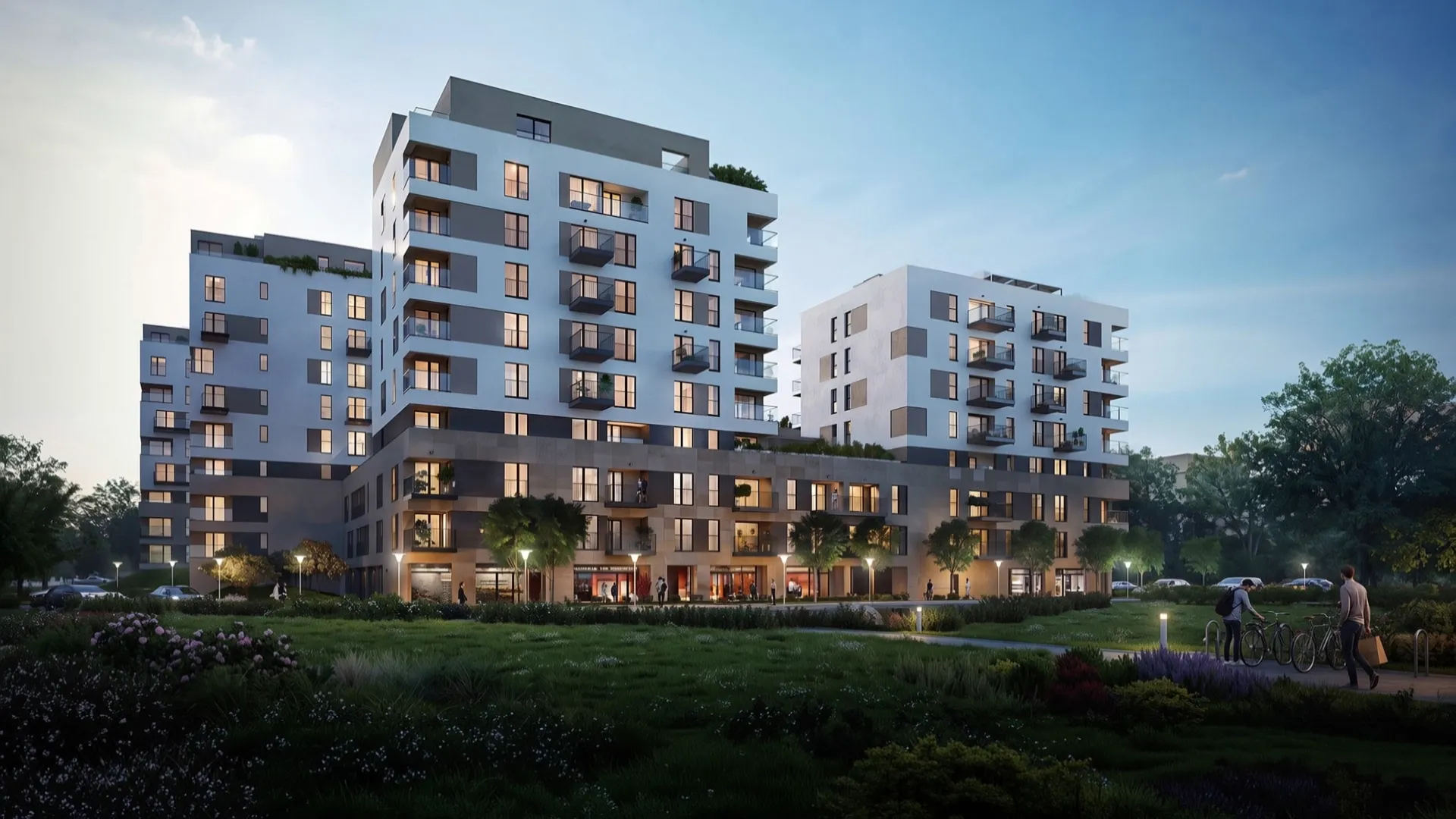 Wizualizacja architektoniczna wielorodzinnego osiedla o wieczornej porze, z podświetlonymi lokalami usługowymi w parterze i zielenią na pierwszym planie